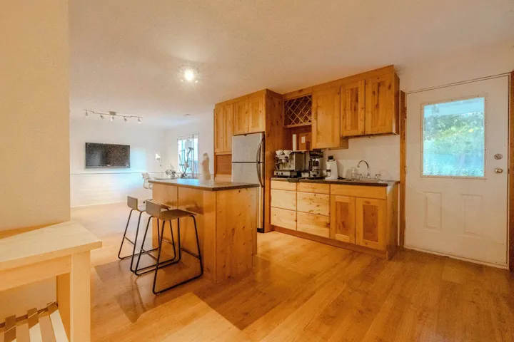 Kitchen featuring a kitchen island, light wood-style flooring, a kitchen bar, freestanding refrigerator, and dark countertops