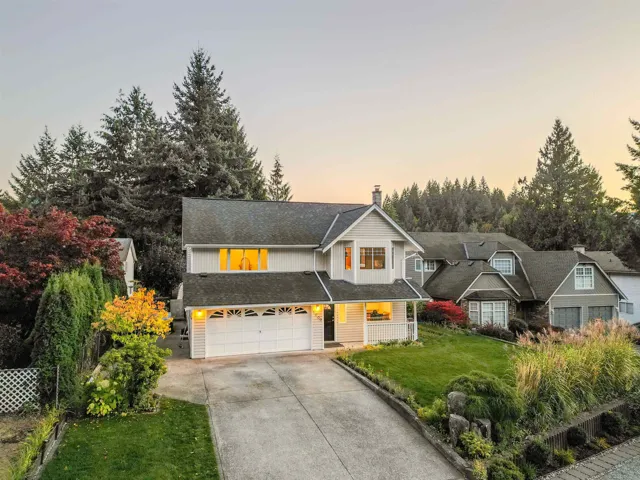 Traditional home with a front yard, a chimney, driveway, board and batten siding, and an attached garage