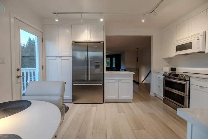 Kitchen featuring appliances with stainless steel finishes, white cabinets, plenty of natural light, and light wood-style floors