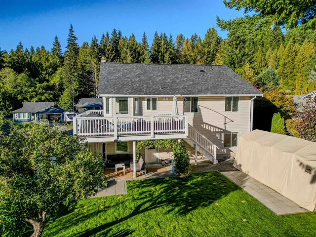 Back of house featuring a patio, a lawn, a deck, stairs, and a chimney