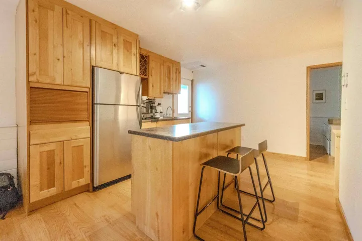 Kitchen with light wood-style floors, a breakfast bar area, freestanding refrigerator, a kitchen island, and light brown cabinetry