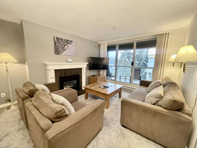 Living area featuring light carpet and a fireplace