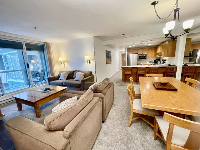 Living room with light colored carpet, rail lighting, and a notable chandelier