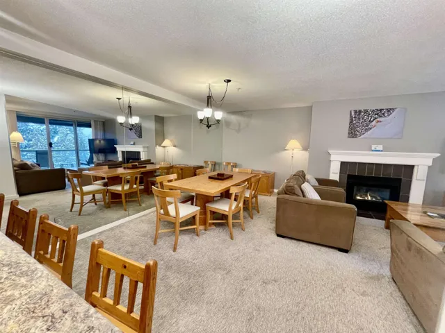 Carpeted dining room featuring a chandelier, a tile fireplace, and a textured ceiling