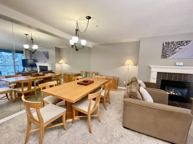 Dining space with a tiled fireplace, an inviting chandelier, and light colored carpet