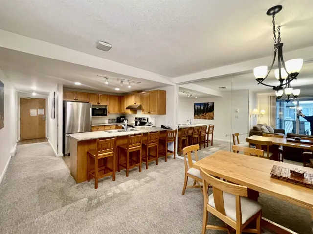 Dining space with light carpet, baseboards, rail lighting, and a textured ceiling
