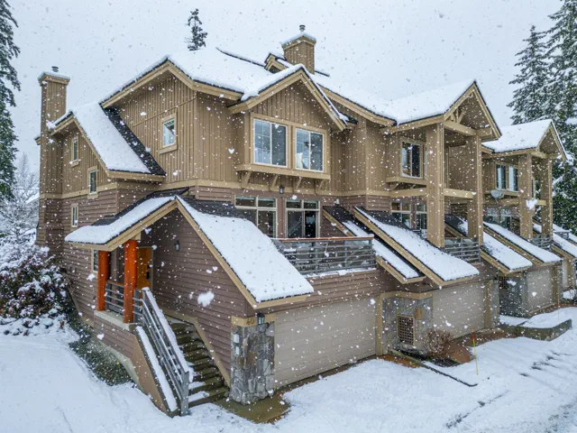 Snow covered house featuring board and batten siding and a chimney