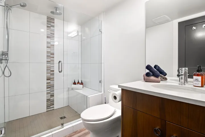 Bathroom with vanity, toilet, and a stall shower