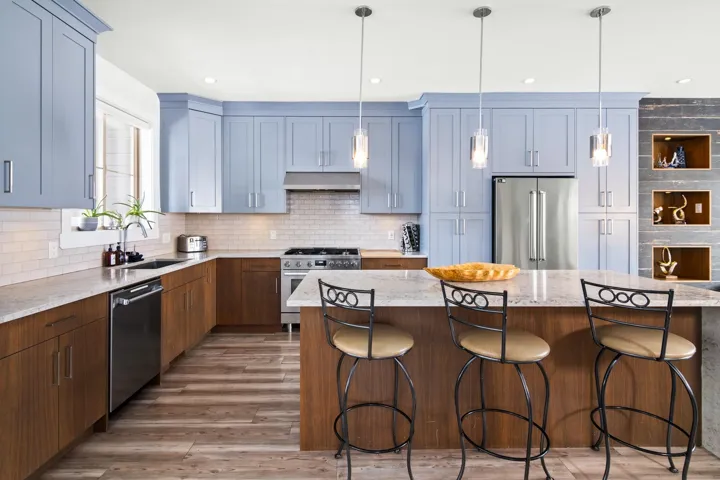 Kitchen featuring light wood-type flooring, a sink, backsplash, ventilation hood, and appliances with stainless steel finishes