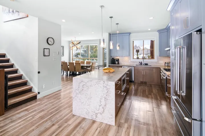 Kitchen featuring a sink, decorative backsplash, stainless steel appliances, light wood-type flooring, and a center island