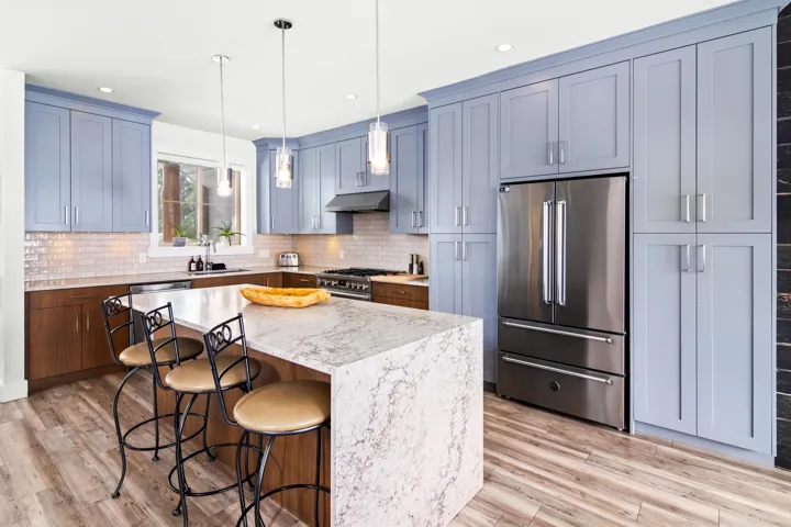 Kitchen featuring under cabinet range hood, premium appliances, a sink, a breakfast bar area, and decorative backsplash