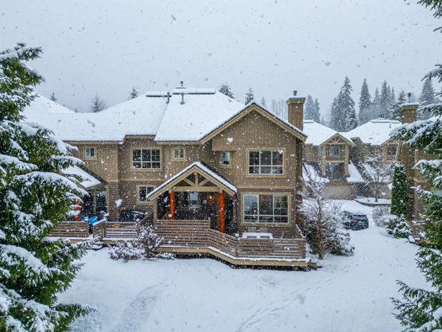 Snow covered back of property featuring a chimney