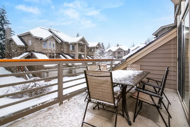 Snow covered back of property featuring a residential view and outdoor dining area
