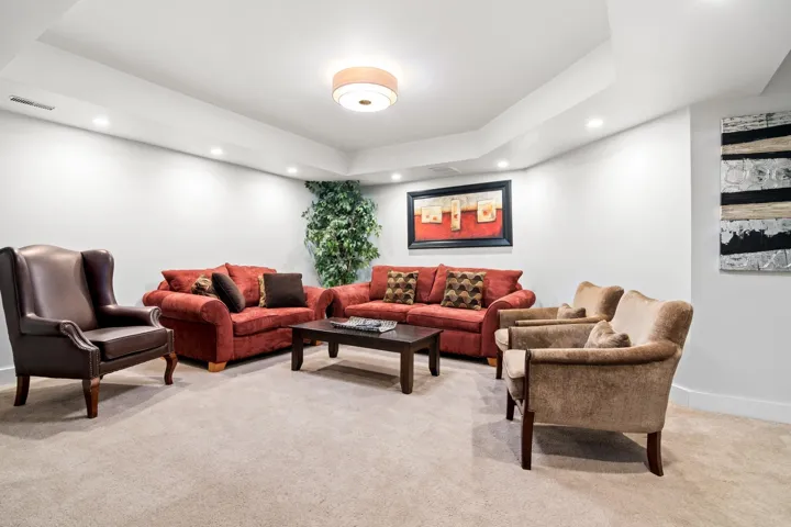 Living room featuring visible vents, a tray ceiling, recessed lighting, baseboards, and light colored carpet