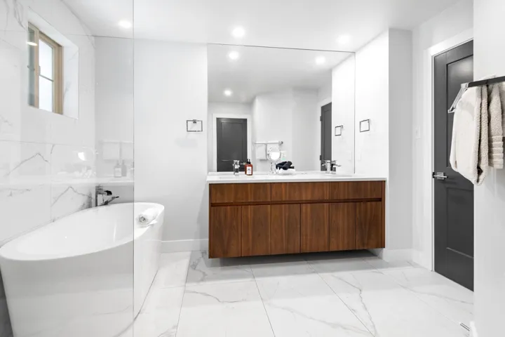 Full bath with double vanity, a freestanding tub, recessed lighting, and marble finish floor