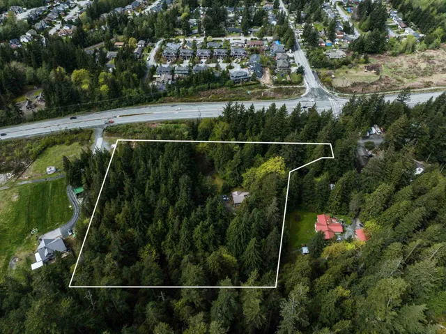 Aerial perspective of suburban area with property parcel outlined and a tree filled landscape
