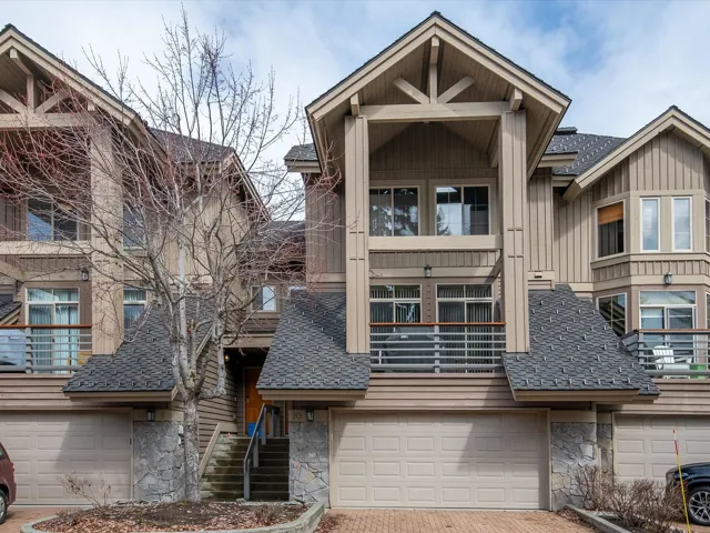 View of front of property featuring stone siding, driveway, roof with shingles, and an attached garage