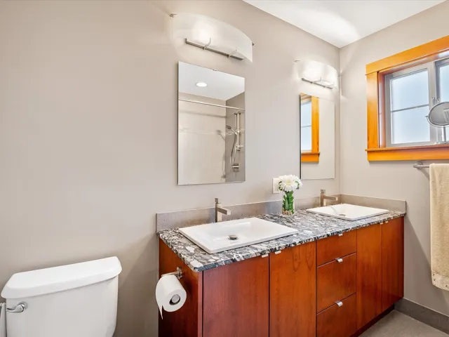 Bathroom featuring double vanity, toilet, a sink, and walk in shower