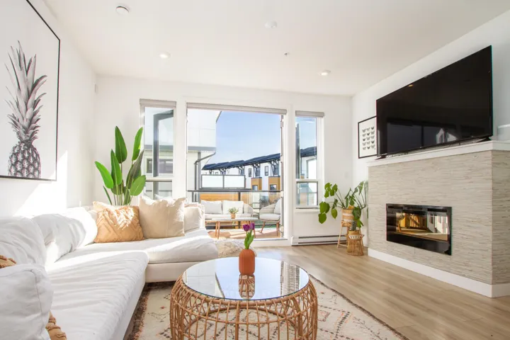 Living room with baseboard heating, recessed lighting, a glass covered fireplace, and light wood-style flooring