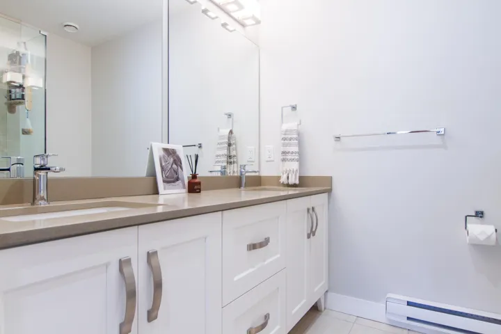 Bathroom featuring baseboard heating, tile patterned floors, double vanity, and a sink