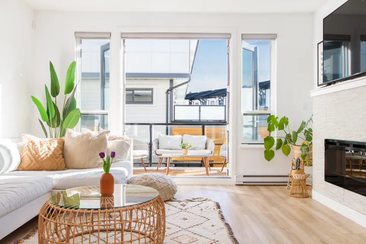 Living room with a fireplace, a baseboard heating unit, wood finished floors, and a healthy amount of sunlight