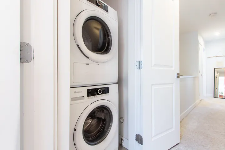 Laundry room featuring carpet, stacked washer / dryer, laundry area, and baseboards