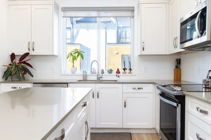 Kitchen featuring a sink, white cabinets, decorative backsplash, and stainless steel appliances