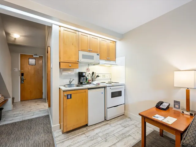 Kitchen featuring white appliances, decorative backsplash, wood tiled floors, light countertops, and under cabinet range hood