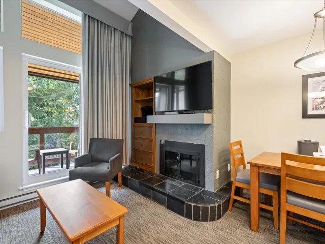 Carpeted living area with a tiled fireplace and a baseboard radiator