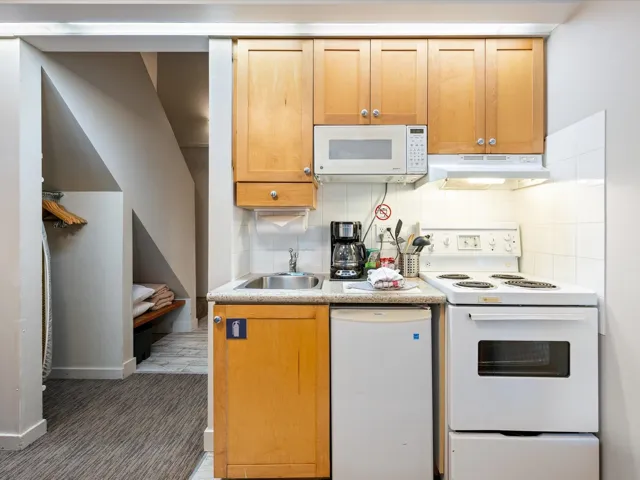 Kitchen featuring white appliances, tasteful backsplash, light countertops, under cabinet range hood, and brown cabinetry