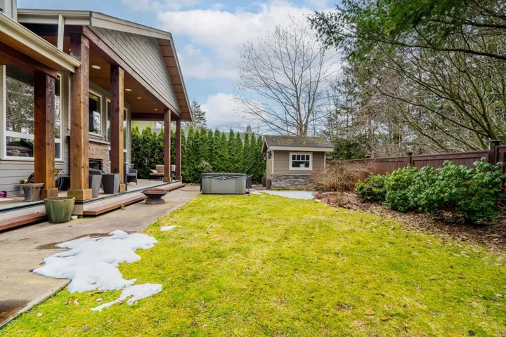 Fenced backyard with a wooden deck, a hot tub, and a storage shed