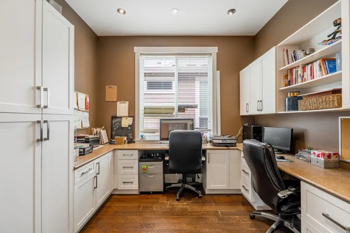 Office area featuring built in desk and dark wood finished floors