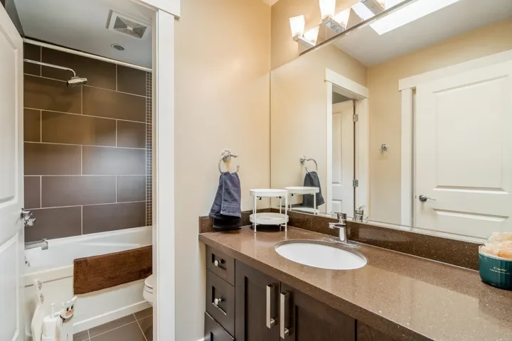 Bathroom featuring vanity, bathtub / shower combination, and dark tile patterned floors