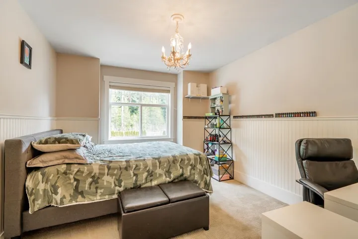 Bedroom featuring wainscoting, a chandelier, and light colored carpet