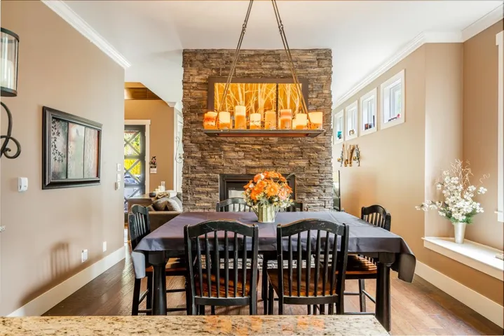 Dining room with crown molding, dark wood-type flooring, a fireplace, and hanging lights