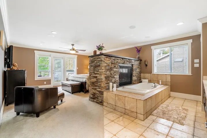 Full bathroom featuring crown molding, a bath, vanity, a fireplace, and ceiling fan