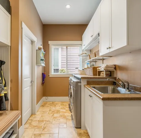 Laundry room featuring cabinet space, washing machine and dryer, stone finish floors, and recessed lighting