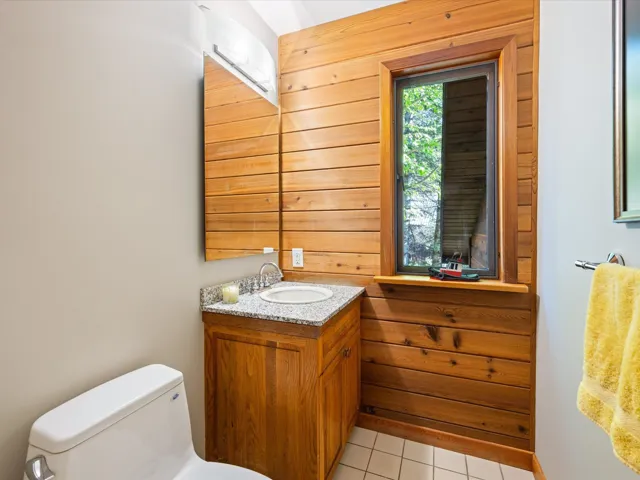 Half bathroom with vanity, light tile patterned floors, and wood walls