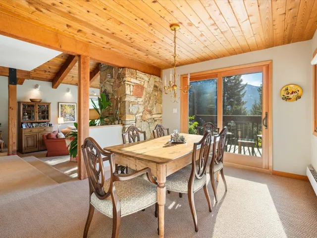 Carpeted dining space with a wooden ceiling with exposed beams and a chandelier