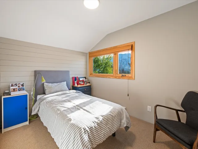 Carpeted bedroom featuring vaulted ceiling and wood walls