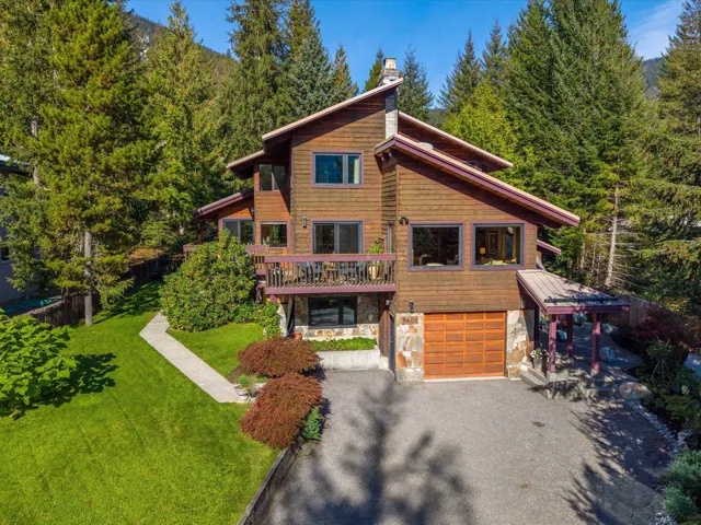 Chalet / cabin with a front lawn, asphalt driveway, stone siding, and a chimney