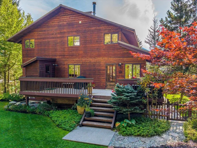 Rear view of property featuring a wooden deck and a lawn