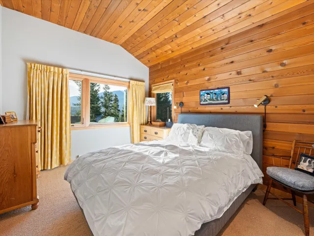 Carpeted bedroom featuring lofted ceiling, wooden ceiling, and wood walls