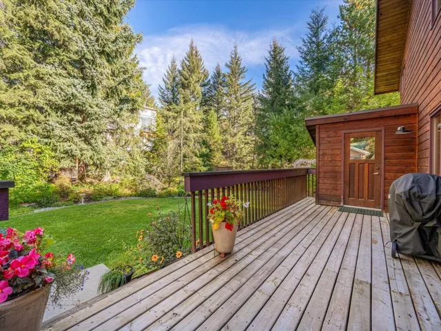 Wooden deck with a lawn, area for grilling, and view of wooded area
