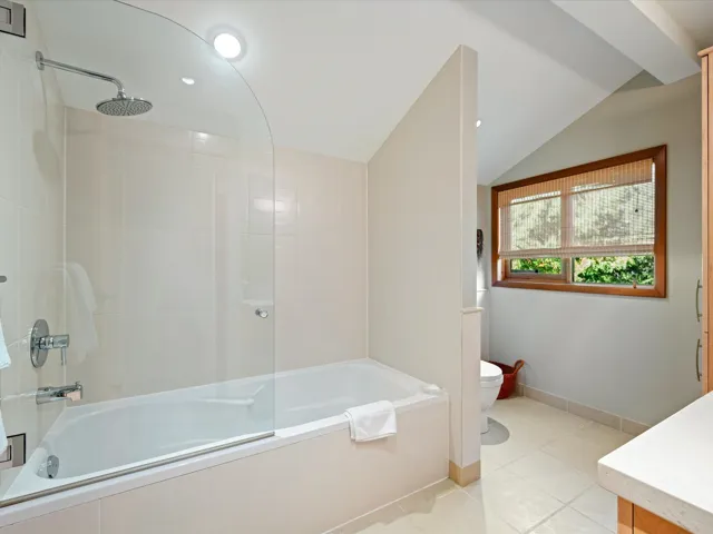 Full bathroom with vaulted ceiling, light tile patterned floors, vanity, tiled shower / bath combo, and recessed lighting
