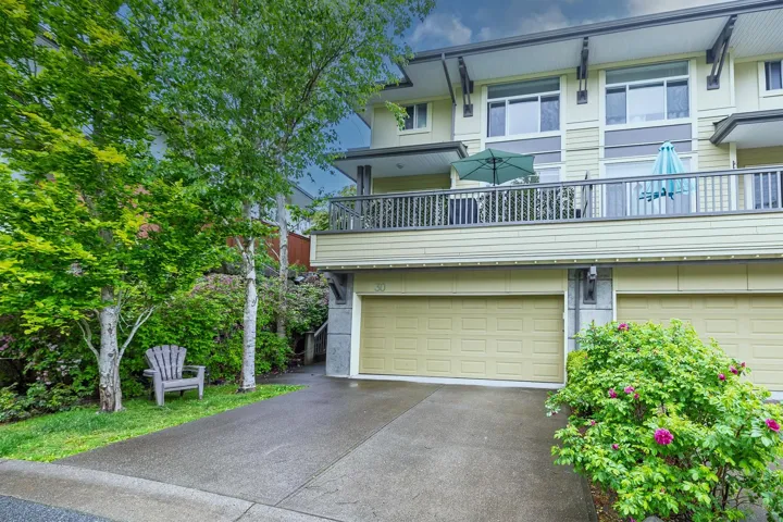 View of front of home featuring a garage, concrete driveway, and a balcony