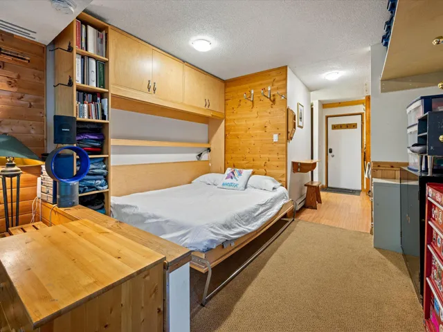 Bedroom featuring wooden walls, a textured ceiling, and light carpet