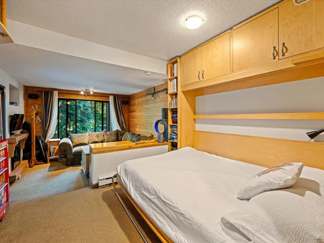 Carpeted bedroom with a textured ceiling, baseboard heating, and wooden walls