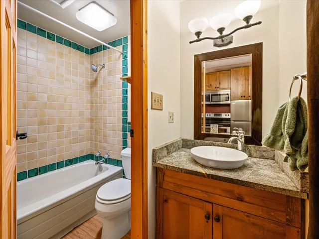 Full bathroom with tub / shower combination, vanity, and light wood-style floors