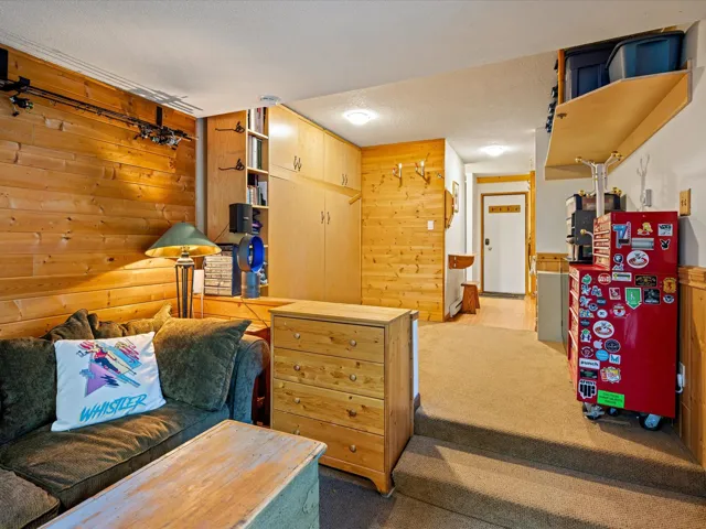 Sitting room featuring wooden walls, carpet flooring, and a textured ceiling